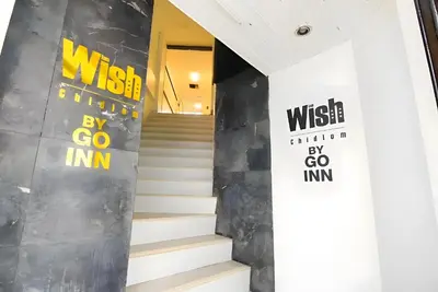 a staircase in a lobby with two signs on the wall at XX Wish Inn Chidlom - วิช อินน์ ชิดลม in Bangkok