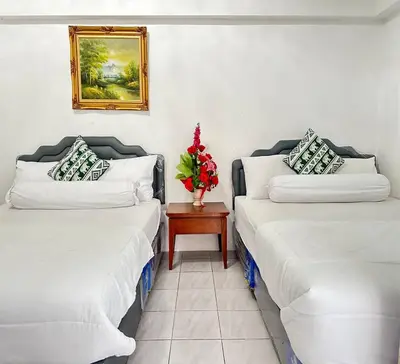 two beds in a room with a vase of flowers on a table at ATHIVAT Royal Pratunam in Bangkok