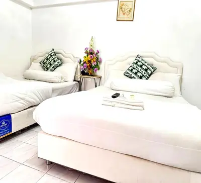 two beds in a room with white walls at ATHIVAT Royal Pratunam in Bangkok