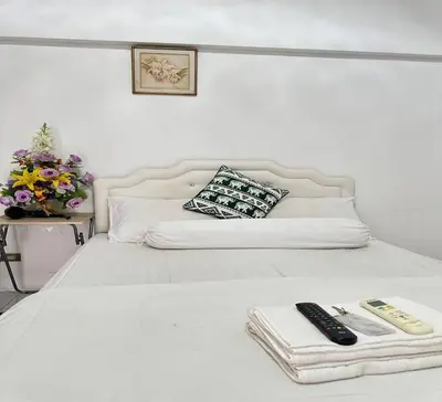 a white bed with two remote controls on it at ATHIVAT Royal Pratunam in Bangkok