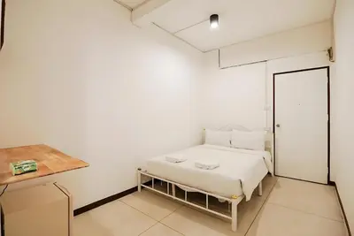 a white bedroom with a bed and a desk at XX GO INN Asiatique Bangkok โก อินน์ เอเชียทีค เจริญกรุง in Bangkok