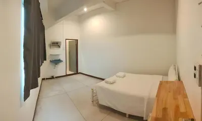 a white room with a bed and a wooden table at XX GO INN Asiatique Bangkok โก อินน์ เอเชียทีค เจริญกรุง in Bangkok