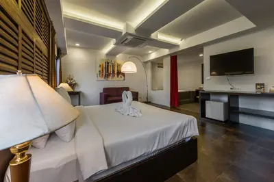 a hotel room with a bed and a flat screen tv at Nanda Heritage Hotel in Bangkok
