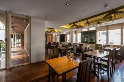 a dining room with wooden tables and chairs at Nanda Heritage Hotel in Bangkok