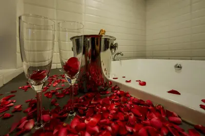 a table with two wine glasses and red rose petals at Nanda Heritage Hotel in Bangkok