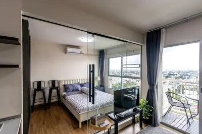 a living room with a couch and a large window at TC Contel At True Digital Park in Amphoe Phra Khanong