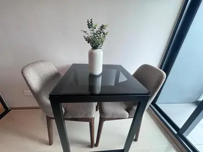 a glass table with a vase on it with two chairs at City Lights Retreat in Bangkok