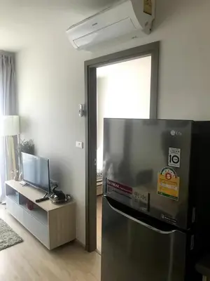 a kitchen with a refrigerator and a table with a television at Home hugs in Bangna
