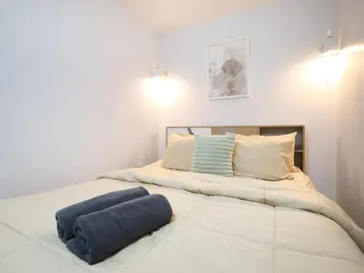 a large white bed with a blue pillow on it at Cozy 2BR Near Impact Arena, LTAT- WiFi Washer near DMK at C2 in Ban Song Hong