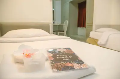 a bed with a book and a candle on it at White Lodge Hotel Bangkok in Bangkok