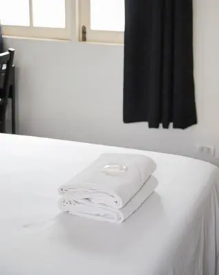 a pile of white towels sitting on a counter in front of a mirror at White Lodge Hotel Bangkok in Bangkok