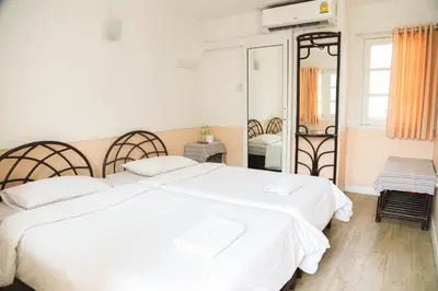 a bedroom with two white beds and a mirror at White Lodge Hotel Bangkok in Bangkok