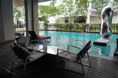 a swimming pool with chairs and a table and a fountain at Luxury room close to BTS in Bangkok