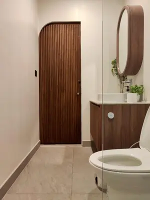 a bathroom with a toilet and a wooden door at Chobjai Hostelry - Chaw Cher Home at Bang Kra Jao in Bang Krasop