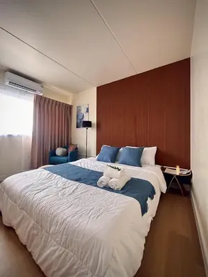 a hotel room with a large bed with two towels on it at Happy House T8 in Thung Si Kan