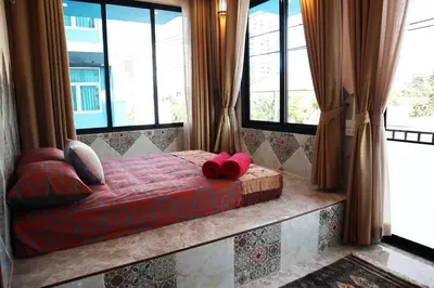 a bed with two red pillows in a room with windows at SKY 10 Convenient near Lumphini Park and MRT in Bangkok