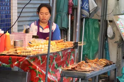 a woman standing in front of a food stand at SKY 14 Vibrant street Cozy n Cool near center in Bangkok