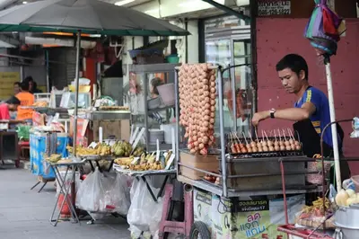 a man standing at a food stand in a market at SKY 18 - 99 feet in the sky in Bangkok