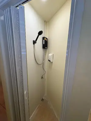 a shower in a bathroom with a blow dryer at Nomad Yard Hostel in Bangkok