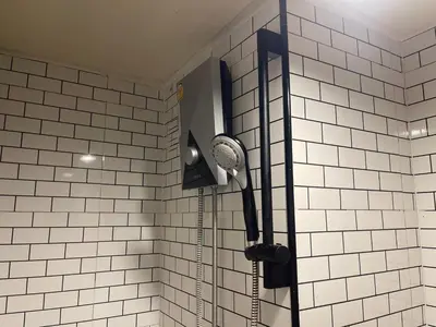 a shower in a bathroom with white tiled walls at Lazy Nest at Impact Muangthong in Thung Si Kan