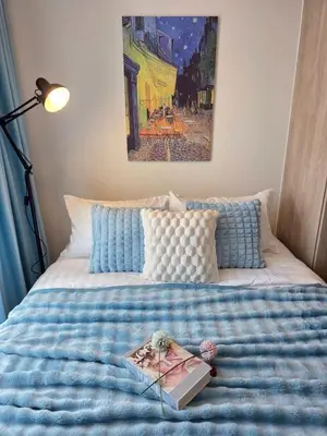 a bed with a blue comforter with a book on it at Modiz Modiza Sukhumvit R1 in Bangkok