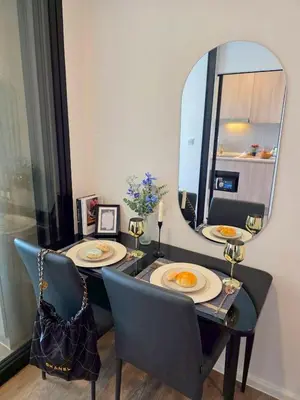 a dining table with two chairs and a mirror at Modiz Modiza Sukhumvit R1 in Bangkok