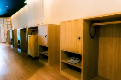 a room with wooden cabinets with white shoes in it at Hakotel in Bang Rak