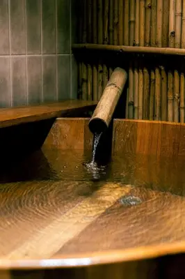a wooden pipe pouring water into a wooden table at Hakotel in Bang Rak