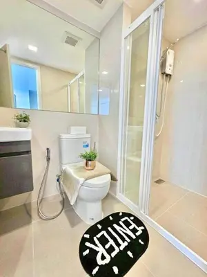 a bathroom with a toilet and a shower and a rug at Modiz Modiza Sukhumvit R3 in Bangkok
