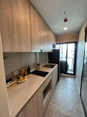 a kitchen with wooden cabinets and a bowl of fruit on the counter at Modiz Modiza Sukhumvit R5 in Bangkok