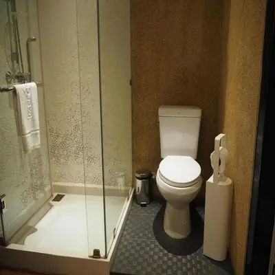 a bathroom with a toilet and a glass shower at Collection O Jasaen Stylish Unique Hotel in Bangkok