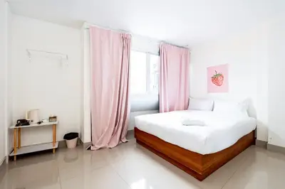 a white bedroom with a large bed with pink curtains at XX Oh My Nap Nana Soi 3 - BTS Nana in Bangkok