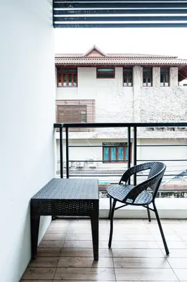 a chair on a balcony with a view of a building at XX Yon INN Sukhumvit Soi 4 - BTS Nana in Bangkok