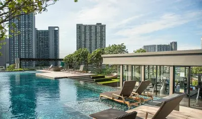 a swimming pool with lounge chairs in a city at 1 Bedroom Bangkok Skyline View Apartment At ON-NUT in Bangkok