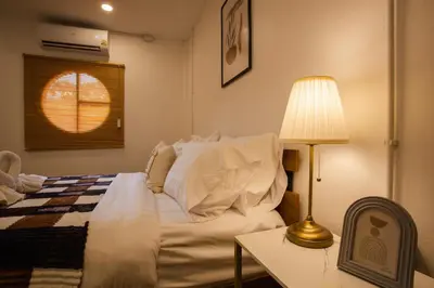 a bedroom with a bed and a table with a lamp at Urban Muji Oasis Ratchada-Lat Phrao Chatuchak MRT in Bangkok
