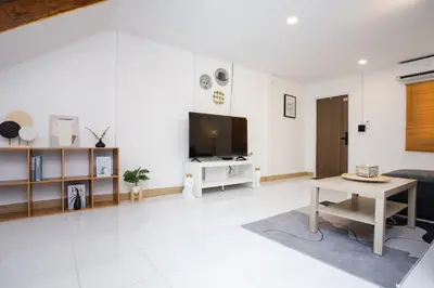 a white living room with a tv and a table at Urban Muji Oasis Ratchada-Lat Phrao Chatuchak MRT in Bangkok
