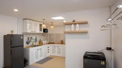 a kitchen with white cabinets and a refrigerator at Urban Muji Oasis Ratchada-Lat Phrao Chatuchak MRT in Bangkok