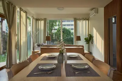 a dining room with a wooden table and chairs at Baan Suanpak in Bangkok
