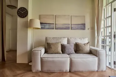 a white couch in a living room with a clock at Baan Suanpak in Bangkok