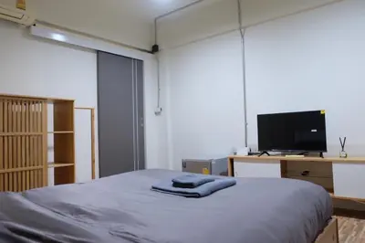 a bedroom with a bed with a tv and a desk at The beeroom by BoonmeeApt in Sathani Sam Sen