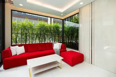 a red couch and stool in a room with a window at Modern Luxury Poolhaus with Lift in Khlong Toei
