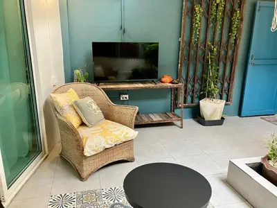 a living room with a wicker chair and a television at Bali Style Rooftop Apartment in Bangkok