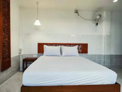 a bedroom with a large white bed with a fan at Tropical Apartments 1 No Stairs easy peasy in Bangkok