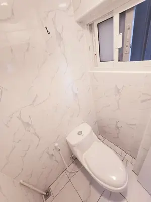 a white bathroom with a toilet and a window at Crane nest 4 lower floor in Bangkok