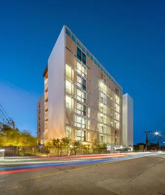 a tall glass building with a street in front of it at SHIN Patara Living Hotel in Bangkok