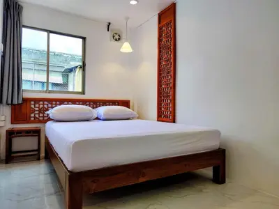 a bedroom with a bed with white sheets and a window at Tropical Apartments 8 Explore Bangkok MRT Lumpini in Bangkok