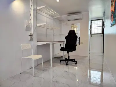 a chair and a desk in a room with white walls at Tropical Apartments 8 Explore Bangkok MRT Lumpini in Bangkok