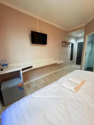 a bedroom with a white bed and a tv on the wall at Luck Hotel Huai Khwang MRT Ratchada in Bangkok