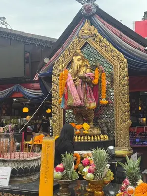 a woman sits in front of a statue in a market at Luck Hotel Huai Khwang MRT Ratchada in Bangkok