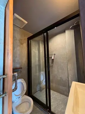 a bathroom with a toilet and a glass shower stall at Sukhum Rajamangala-Phatthanakan Rooms in Bangkok